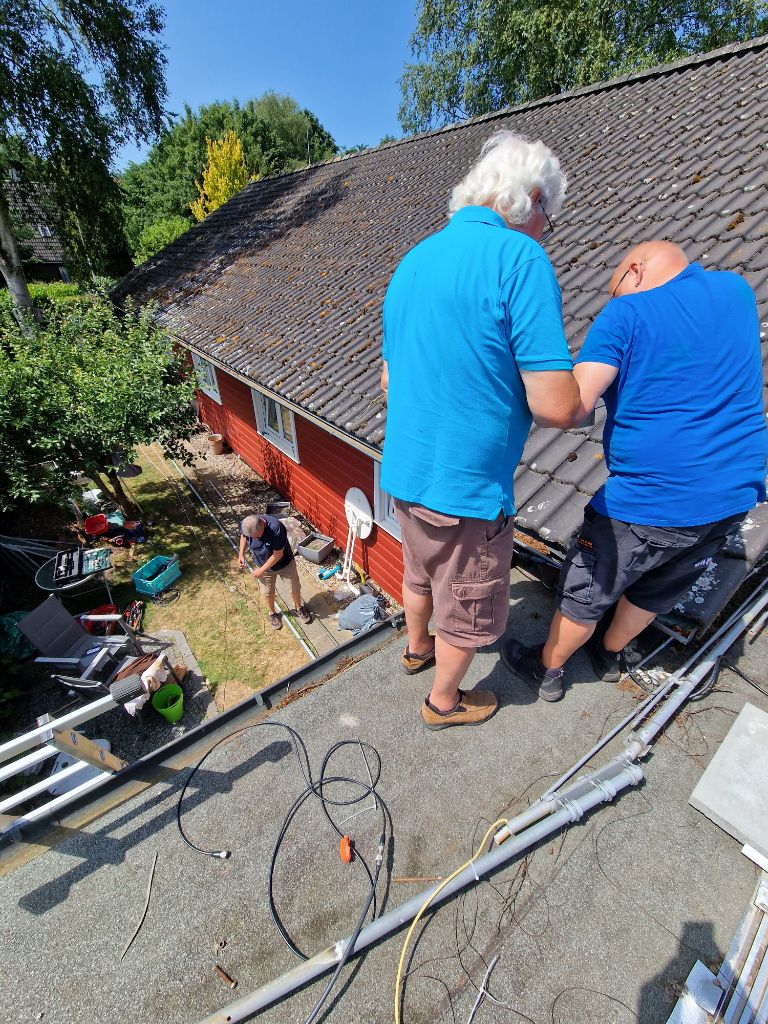 Zwei schleswiger Funkamateure stehen auf dem Carportdach und überprüfen eine Antenne.