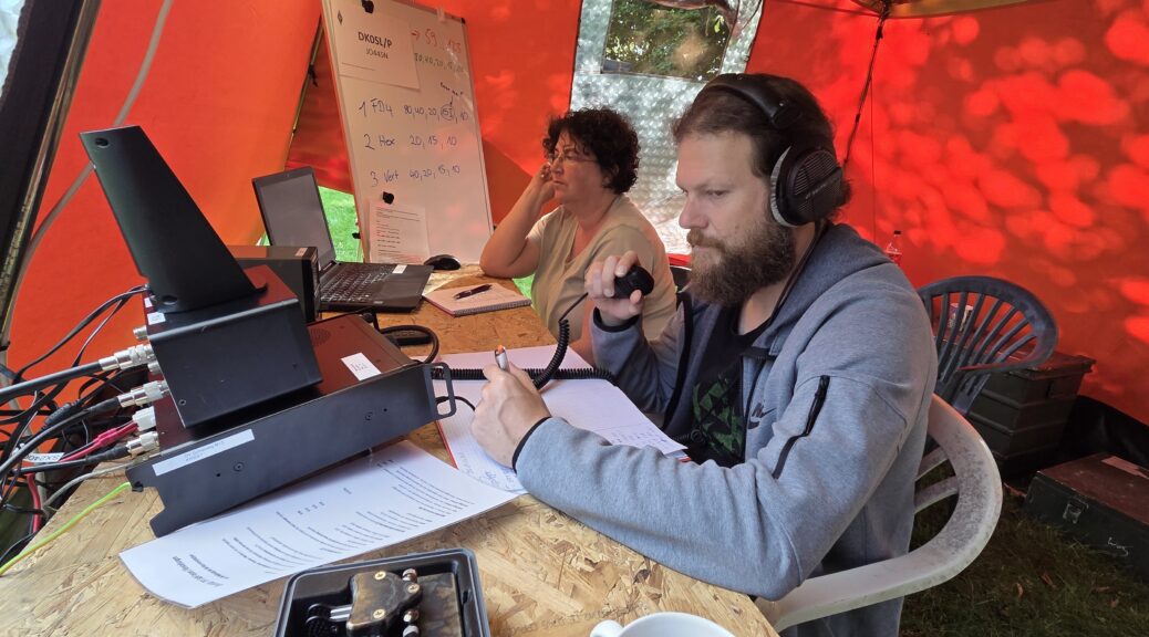 Zwei Funkamateure, ein Mann und eine Frau sitzen im Operatorzelt während des Fielddays in Nübel