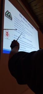 OVV Oliver DO7OMB erklärt mit einem Zeigestock die Funktion von MeshCom 4.0 an einem Beamerbild im Ruhekrug.