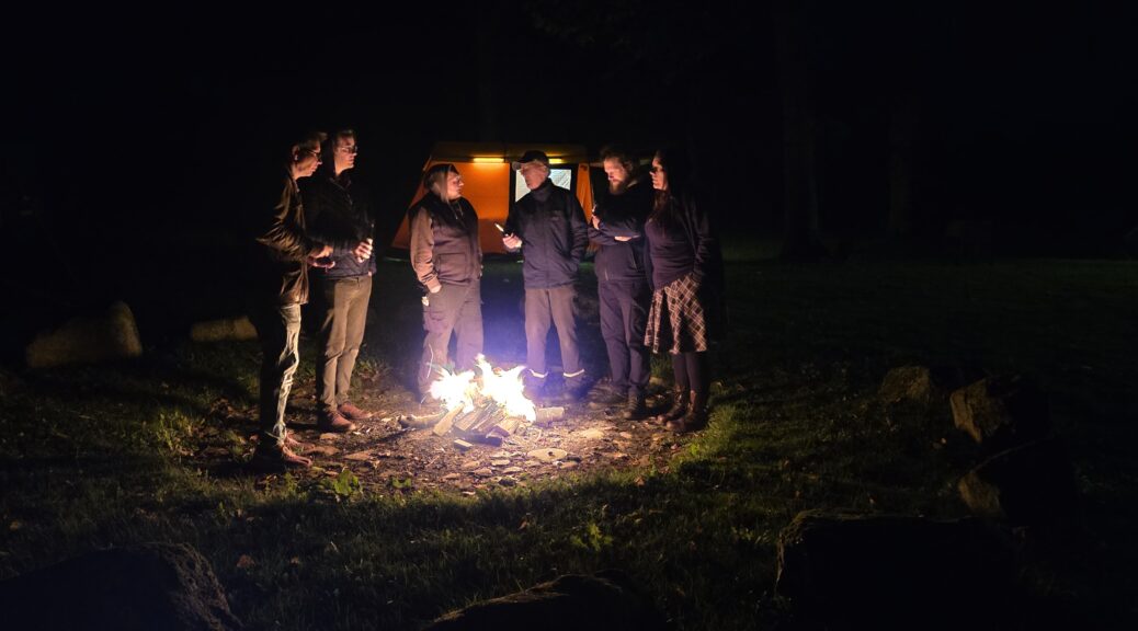 Eine Gruppe von schleswiger Funkern steht um ein Lagerfeuer auf dem Grillplatz in Nübel.
